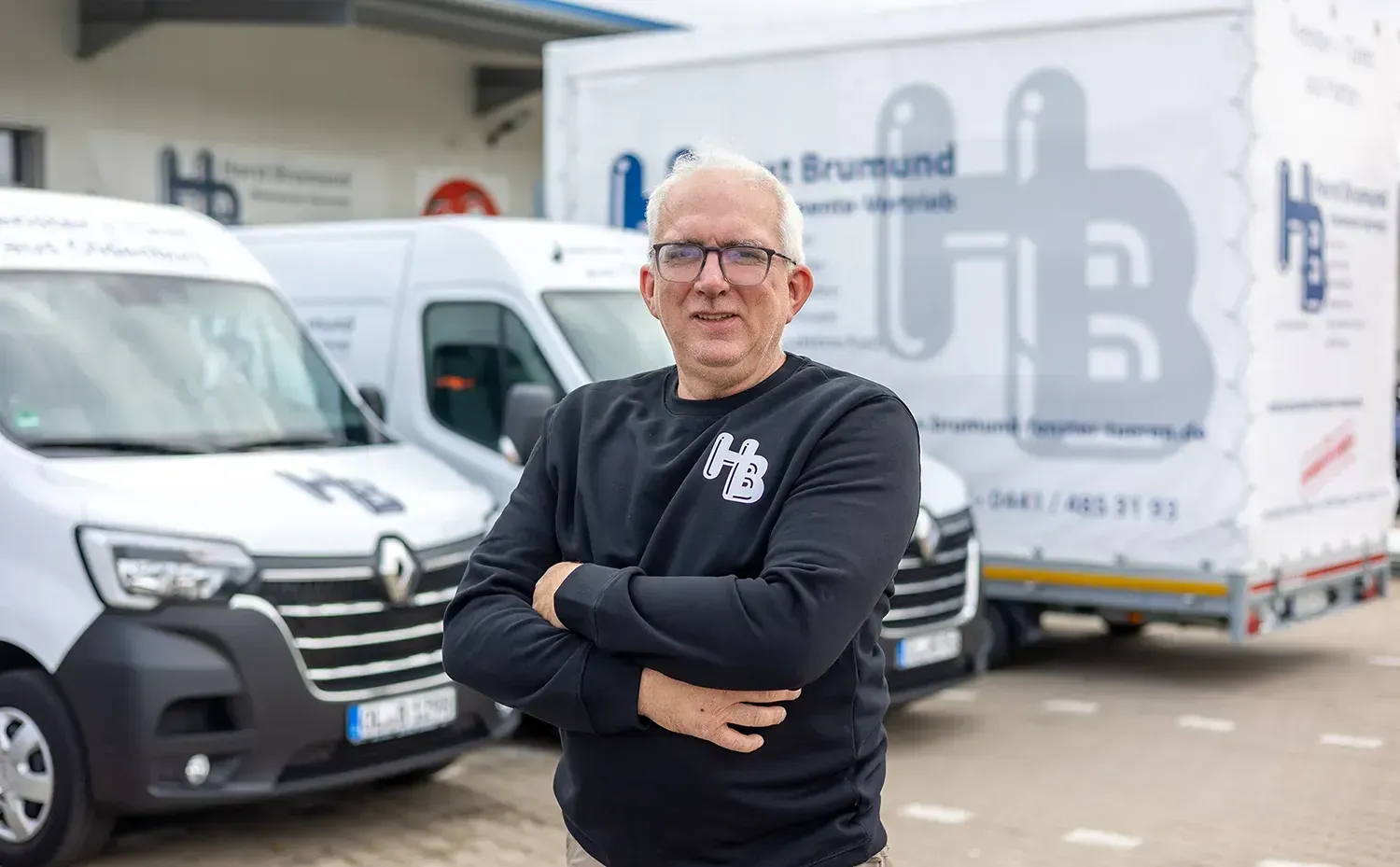 Ein Mann steht vor einer Reihe weißer Lieferwagen.