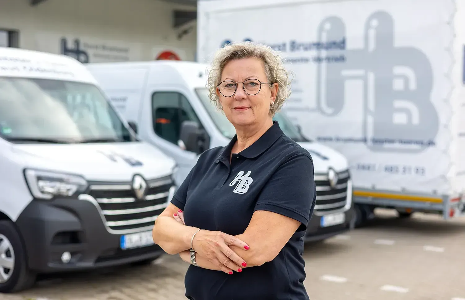 Eine Frau steht vor einer Reihe weißer Lieferwagen.