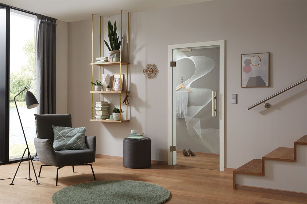 Ein Wohnzimmer mit einer weißen Tür, einem Stuhl, einer Lampe und einer Treppe.