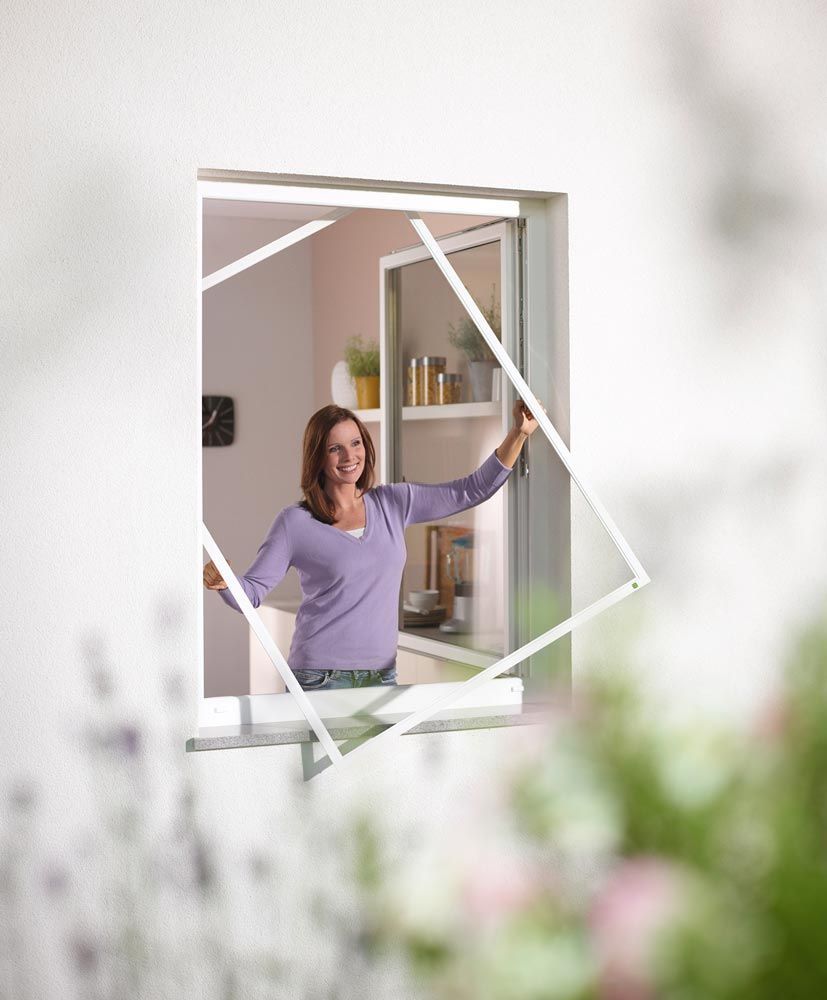 Eine Frau schaut aus einem Fenster mit Moskitonetz.