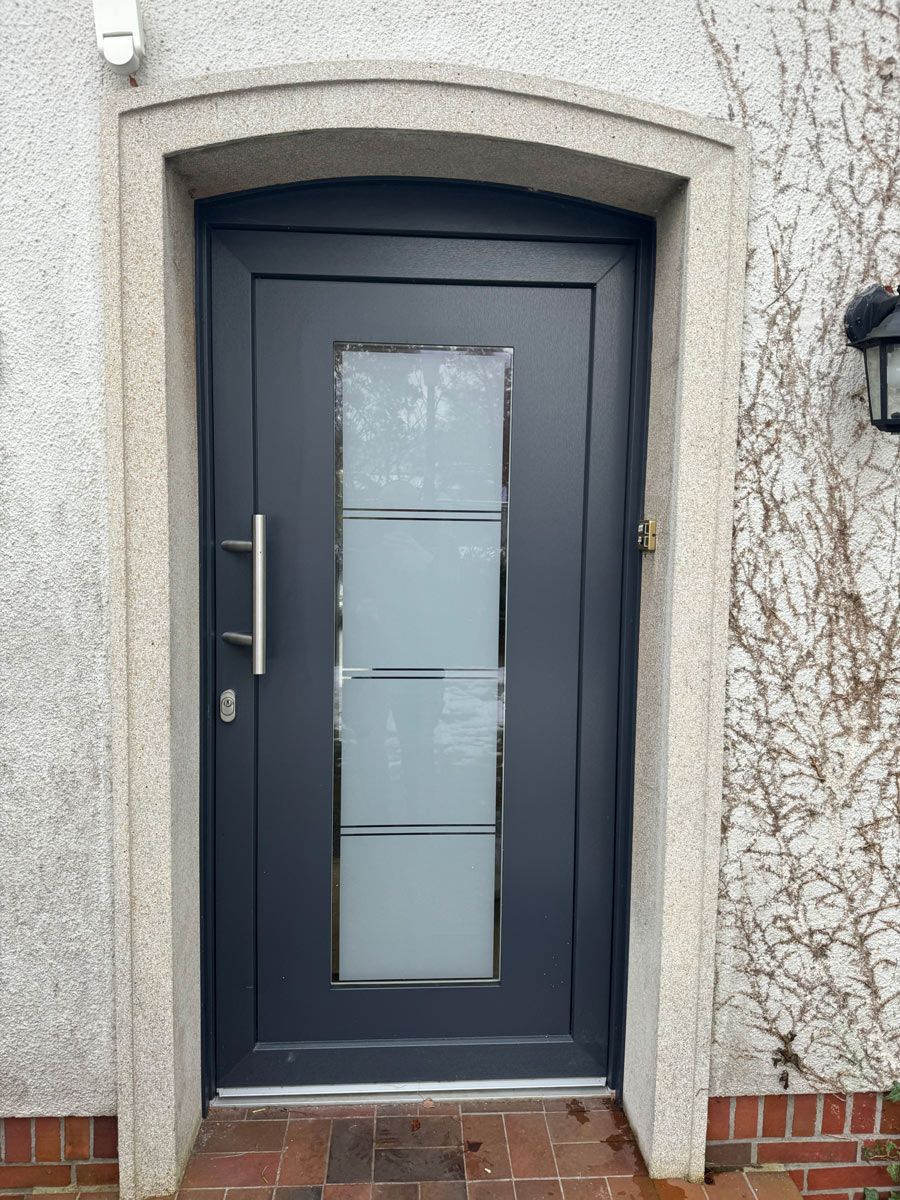 An der Seite eines Gebäudes befindet sich eine schwarze Tür mit einem Glasfenster.