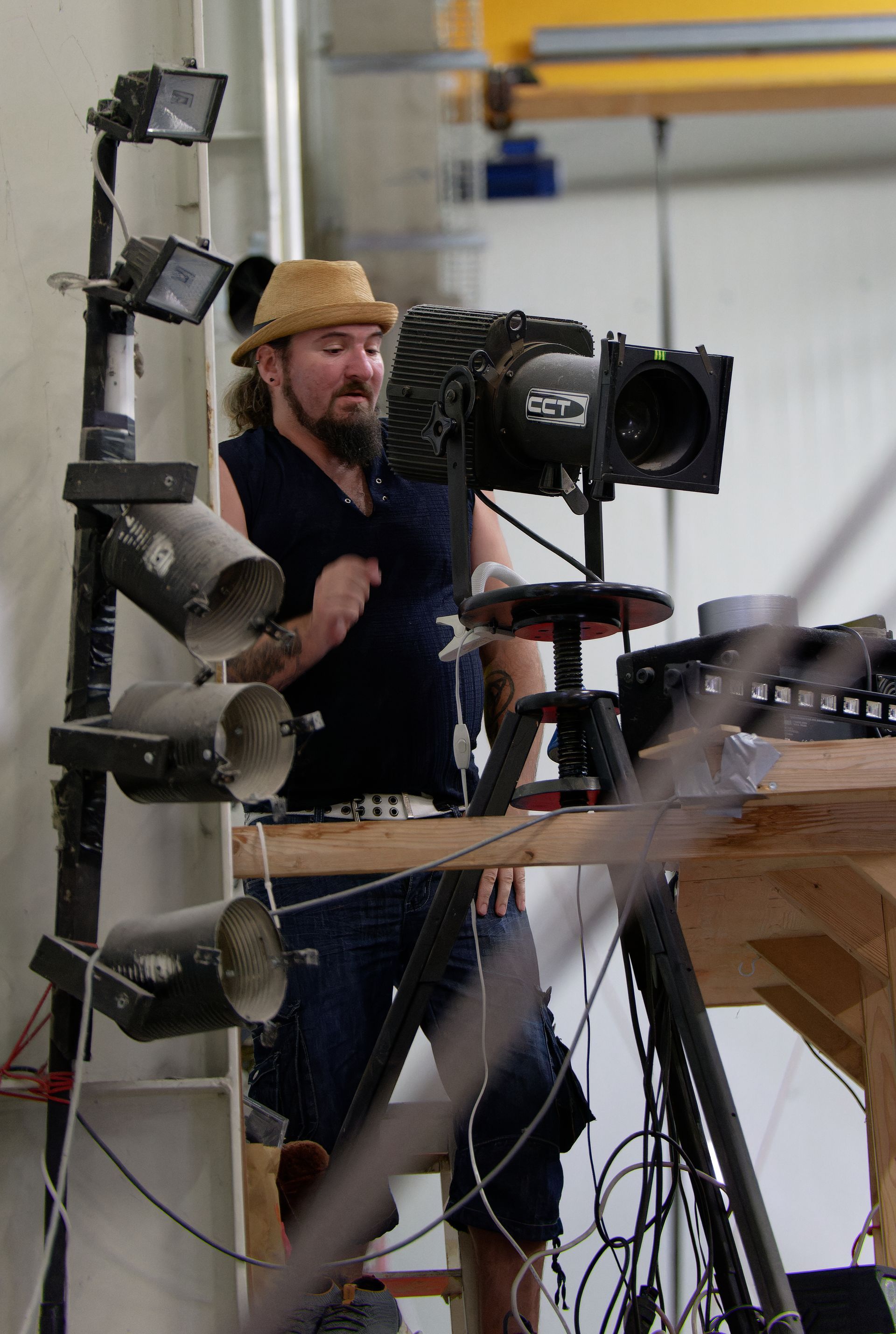 Salle d'entraînement de cirque : une acrobate aérienne dans les airs, d'autres spectateurs au sol ; tapis, cordes et une grande pile de tapis.