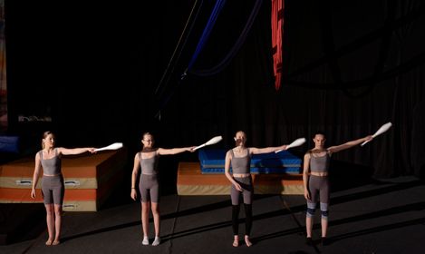 Silhouette d'une personne suspendue à des tissus aériens sur fond bleu avec une lumière vive.
