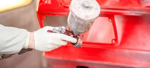 Una persona está rociando pintura roja sobre un objeto rojo.