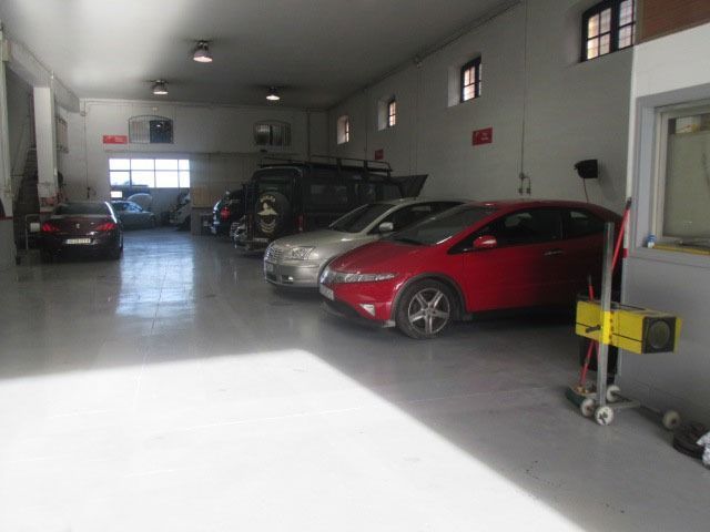 Un coche rojo está aparcado en medio de un garaje.