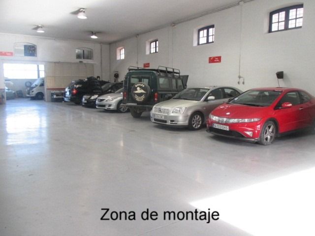 Una fila de coches están aparcados en un garaje con las palabras zona de montaje encima de ellos