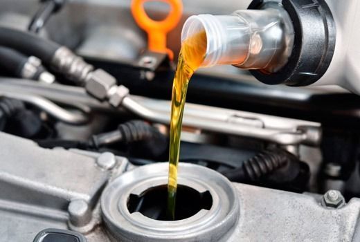 Un primer plano de una persona vertiendo aceite en el motor de un automóvil.