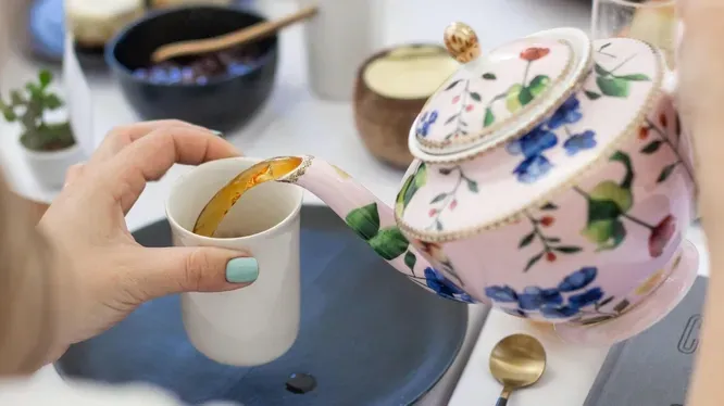 A person is pouring tea into a cup from a teapot.