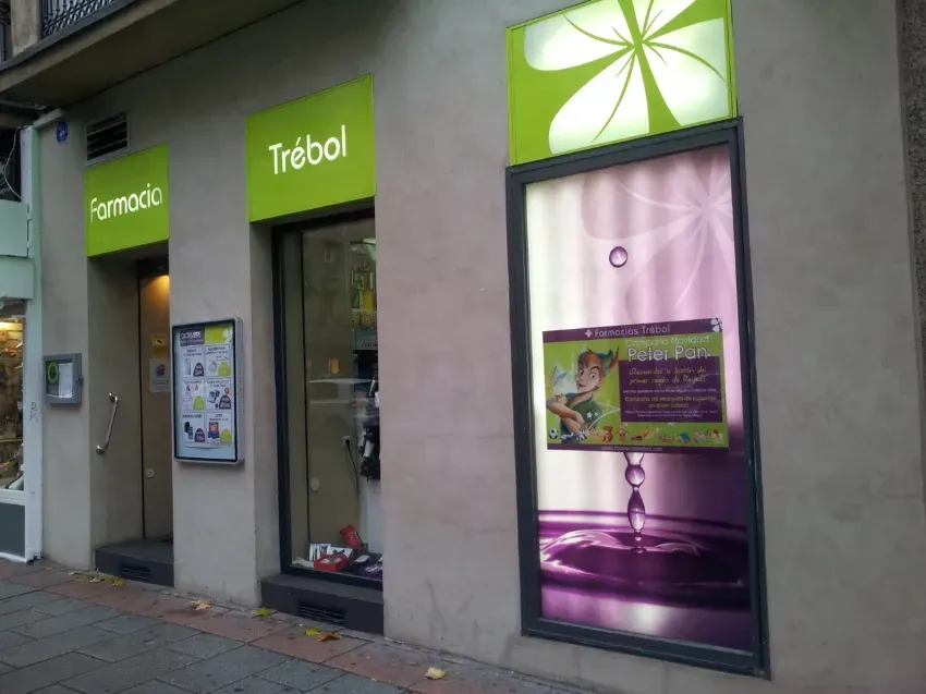 Escaparate de Trébol con carteles verdes y un escaparate morado en una acera de la ciudad