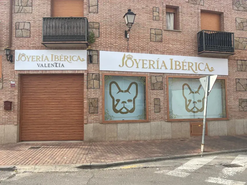 Escaparate de Joyería Ibérica con las persianas cerradas y un escaparate de cristal con gráficos de caras de perros