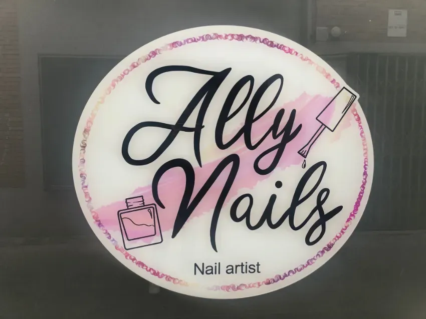 Logotipo circular de artista de uñas «Ally Nails» en negro y rosa, con un frasco de esmalte y dibujos de esmalte de uñas