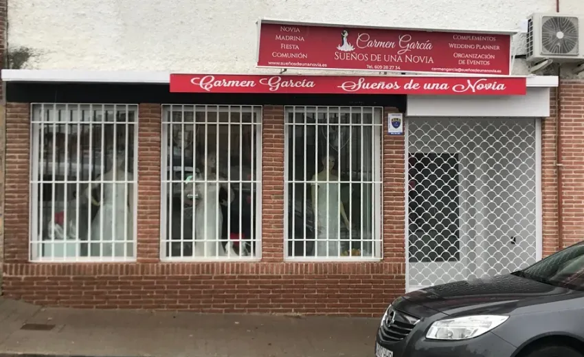 Local con toldo rojo, ventanas enrejadas y un coche aparcado en la calle.