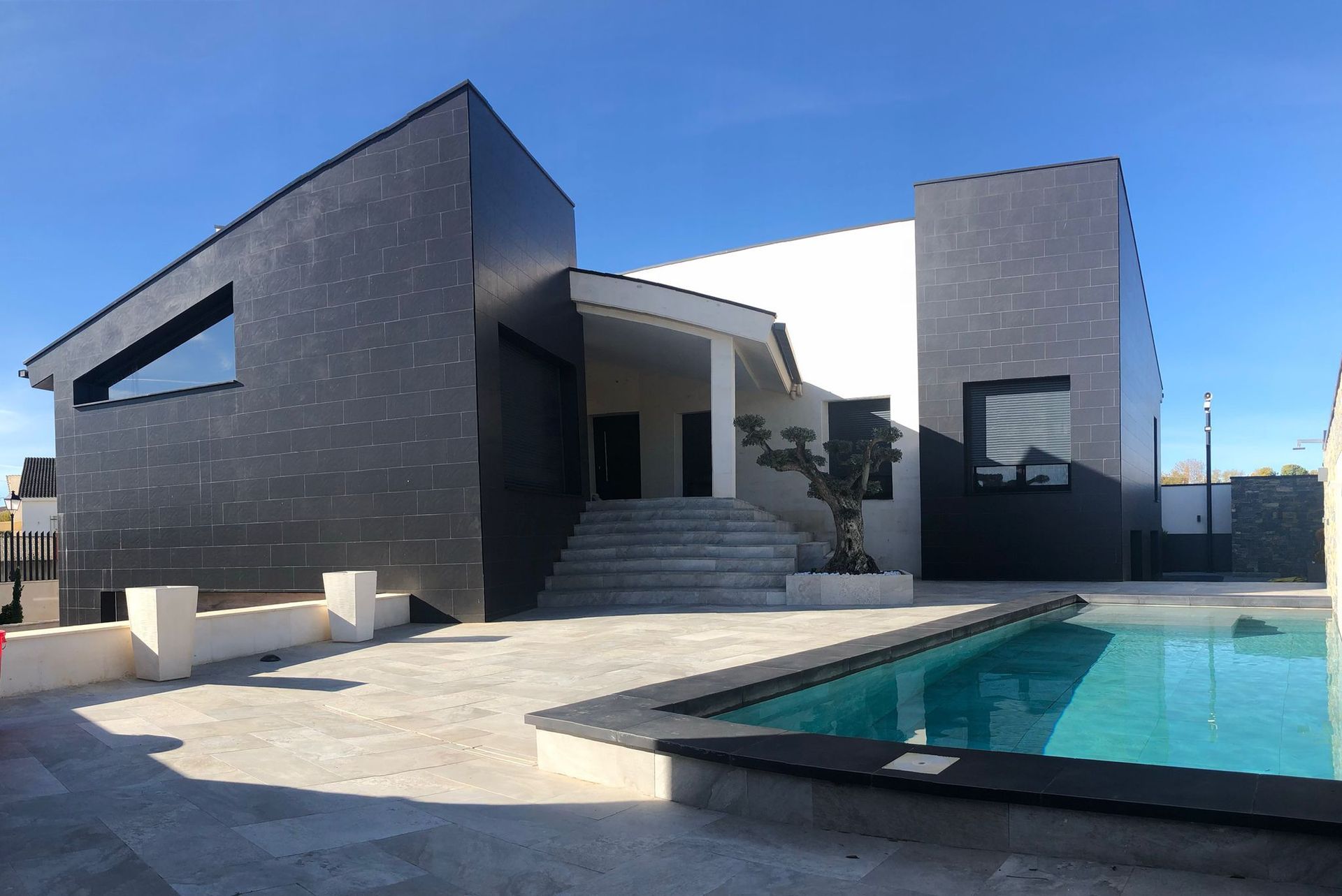 Patio trasero con piscina junto a una casa moderna y tumbonas