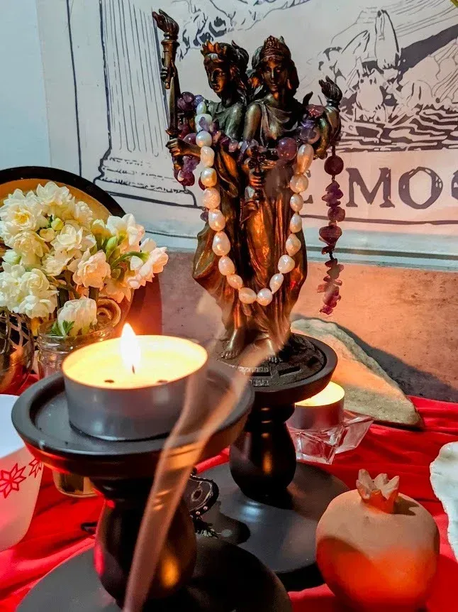 Altar devocional iluminado con una estatua de una deidad hindú, velas, flores y humo de incienso.