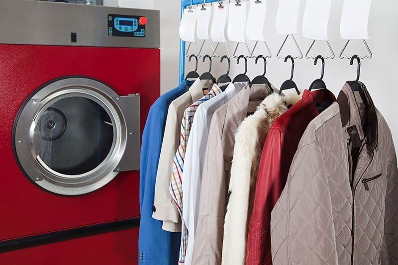 La ropa está colgada en una lavandería al lado de una lavadora.