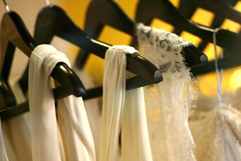 Un montón de vestidos blancos están colgados en un perchero.