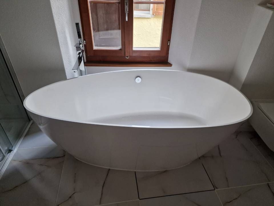 Une baignoire blanche se trouve dans une salle de bain à côté d'une fenêtre.