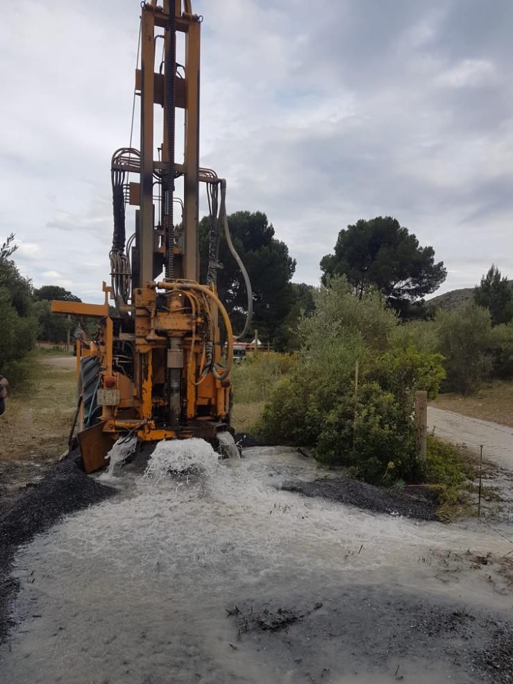 Plataforma de perforación amarilla sobre una superficie de grava, fondo de cielo azul.