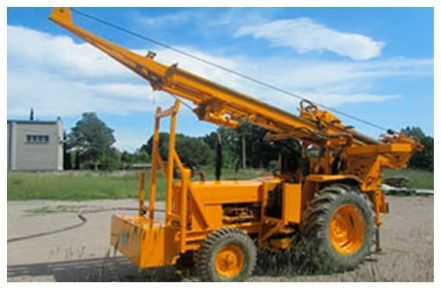 Máquina perforadora amarilla en un campo con un brazo de perforación elevado.