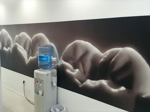 Un dispensador de agua en una habitación con una imagen de dientes en la pared.