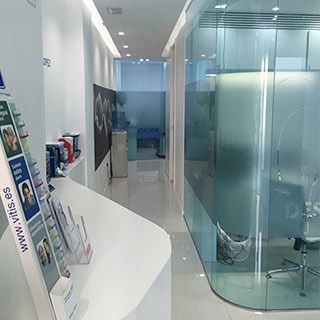 Un pasillo en un consultorio dental con una pared de vidrio y una silla.