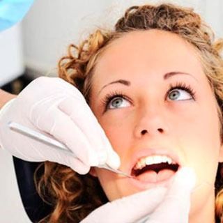 Una mujer está siendo examinada por un dentista.