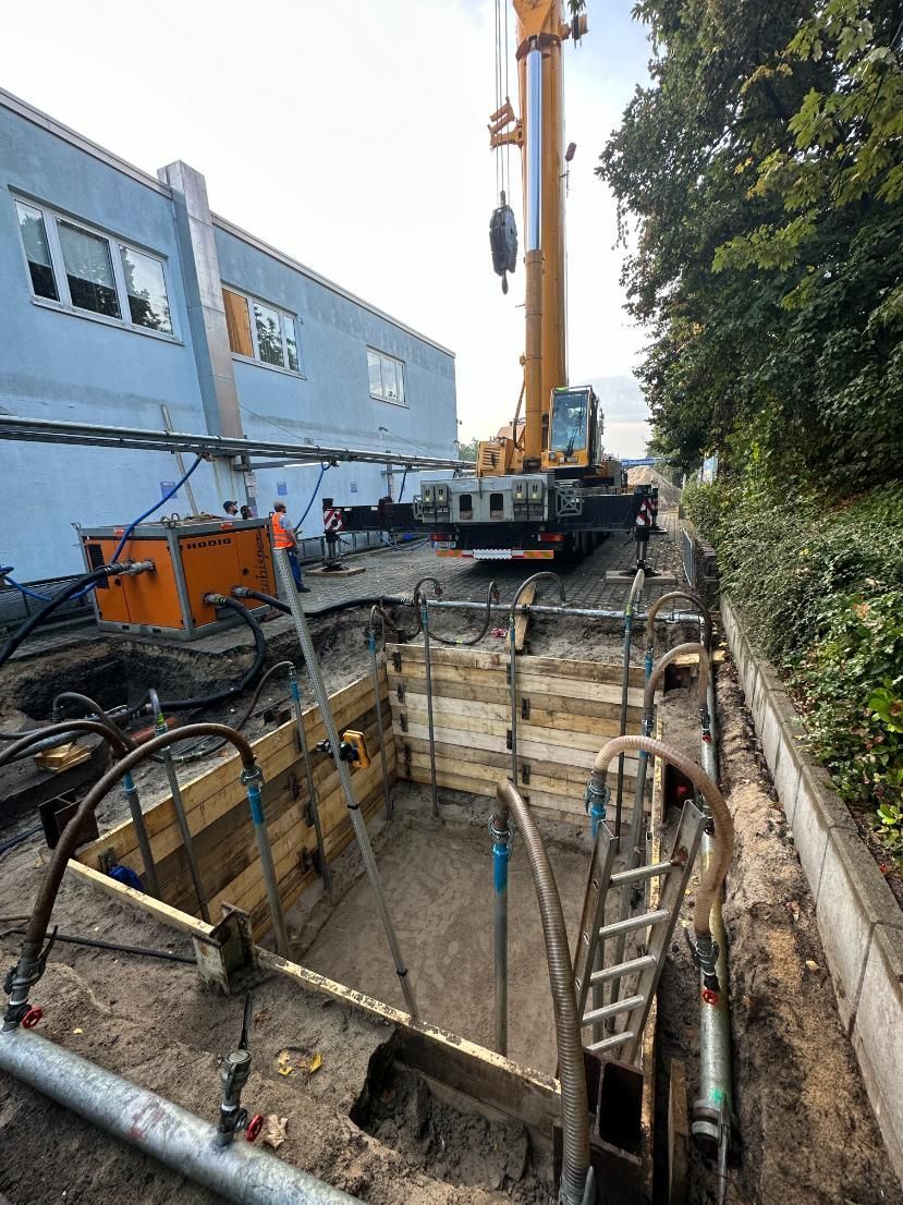 Baustelle mit Kran, Graben und Gebäude.