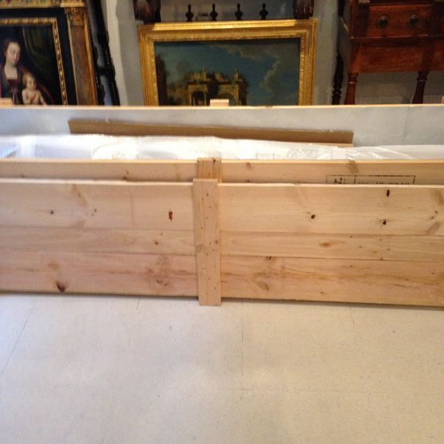 Caja de madera que contiene obras de arte, en el interior, con pinturas enmarcadas en el fondo.