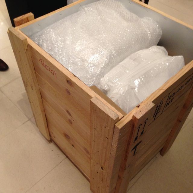 Caja de envío de madera que contiene paquetes envueltos en plástico de burbujas.