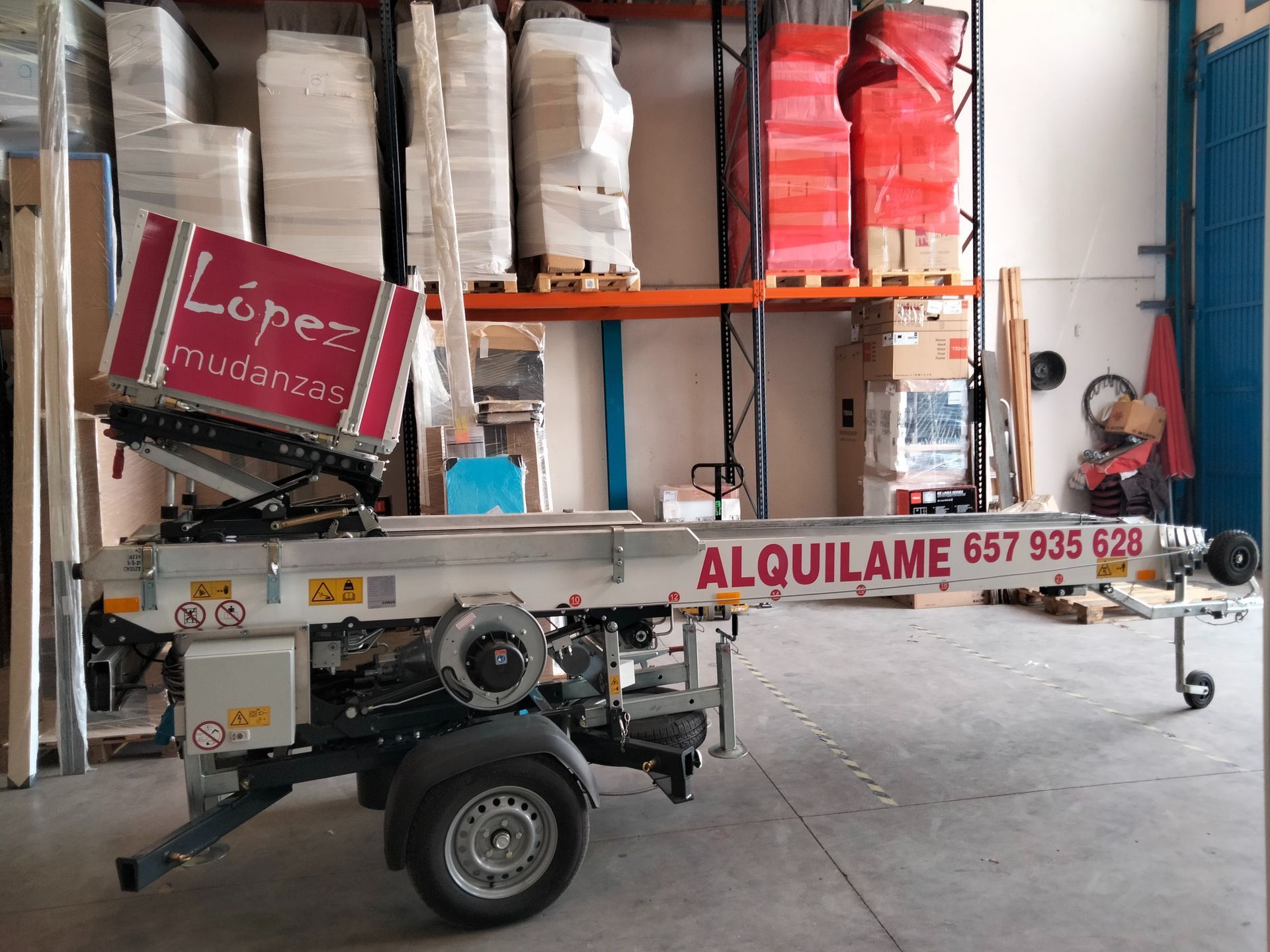 En una nave se encuentra una plataforma elevadora sobre camión con señalización