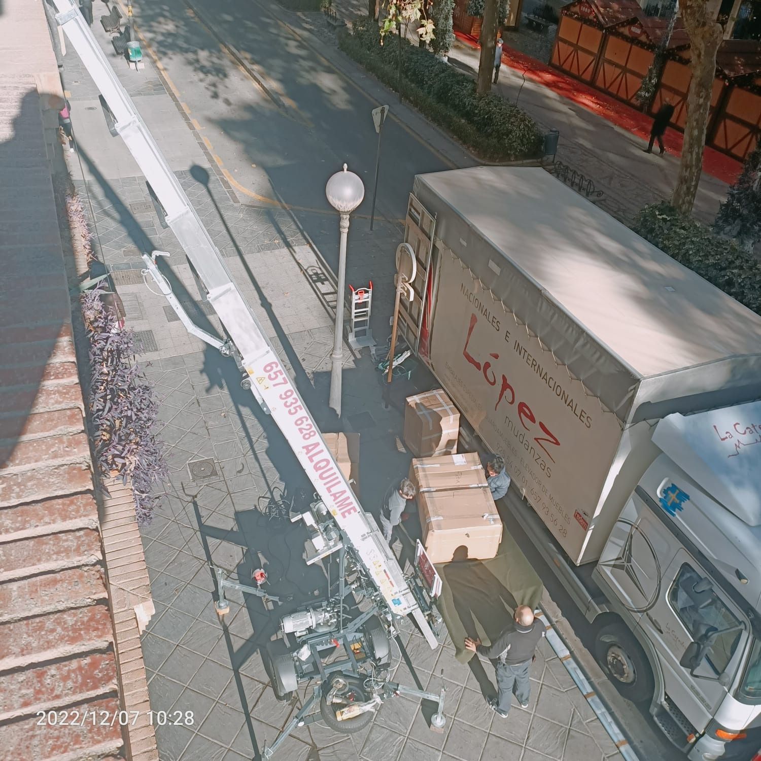 Camión de mudanzas con elevador; trabajadores descargando cajas. Escena callejera, Madrid, España.