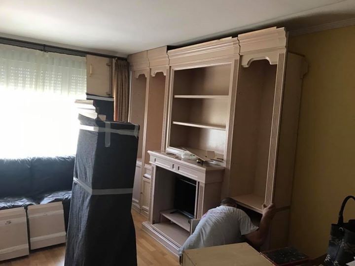 Una habitación con un centro de entretenimiento empotrado a medida en proceso de montaje. Una persona trabaja en él.