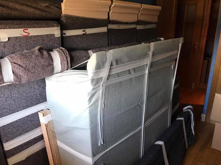 Varios colchones y rellenos apilados y envueltos en una habitación, probablemente para envío o almacenamiento.