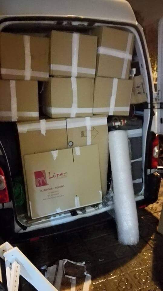 Furgoneta abierta cargada con cajas de cartón, materiales de embalaje y equipos.