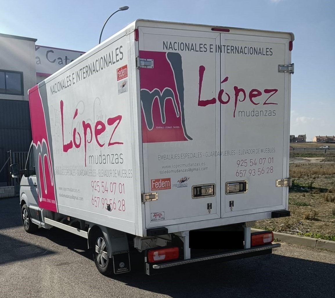 Camión de mudanzas López, color blanco, con letras y logo en color rojo; estacionado al aire libre.