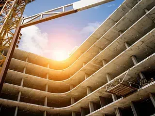 Sitio de construcción con un marco de edificio de varios pisos en construcción, luz solar brillante.