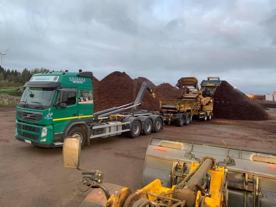 Vihreä kuorma-auto on pysäköity maa-aineskasan eteen.