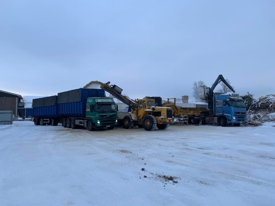 Useita työkoneita on pysäköity lumiselle tontille.