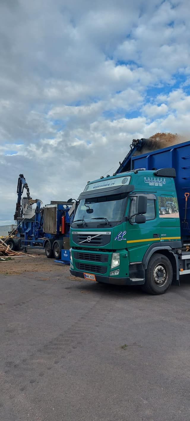 Vihreä kuorma-auto on pysäköity  sinisen kuorma-auton viereen.