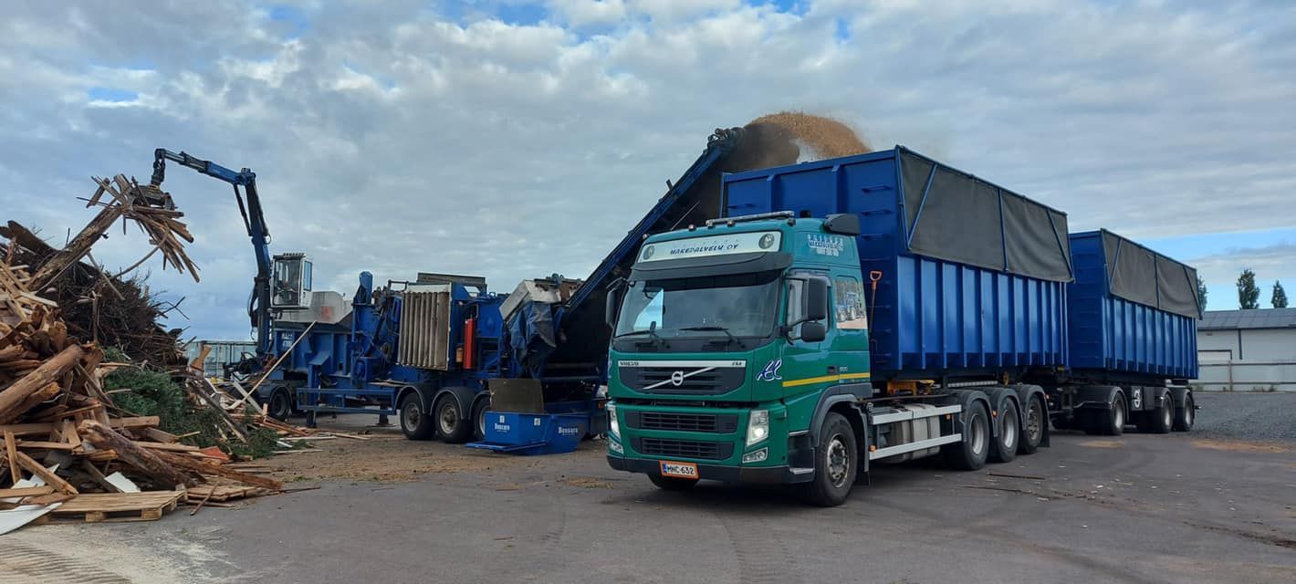 Vihreään kuorma-autoon lastataan haketta.