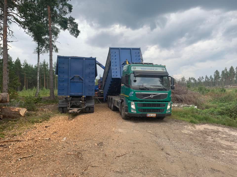 Vihreä kuorma-auto ja sininen peräkärry odottamassa lastausta.