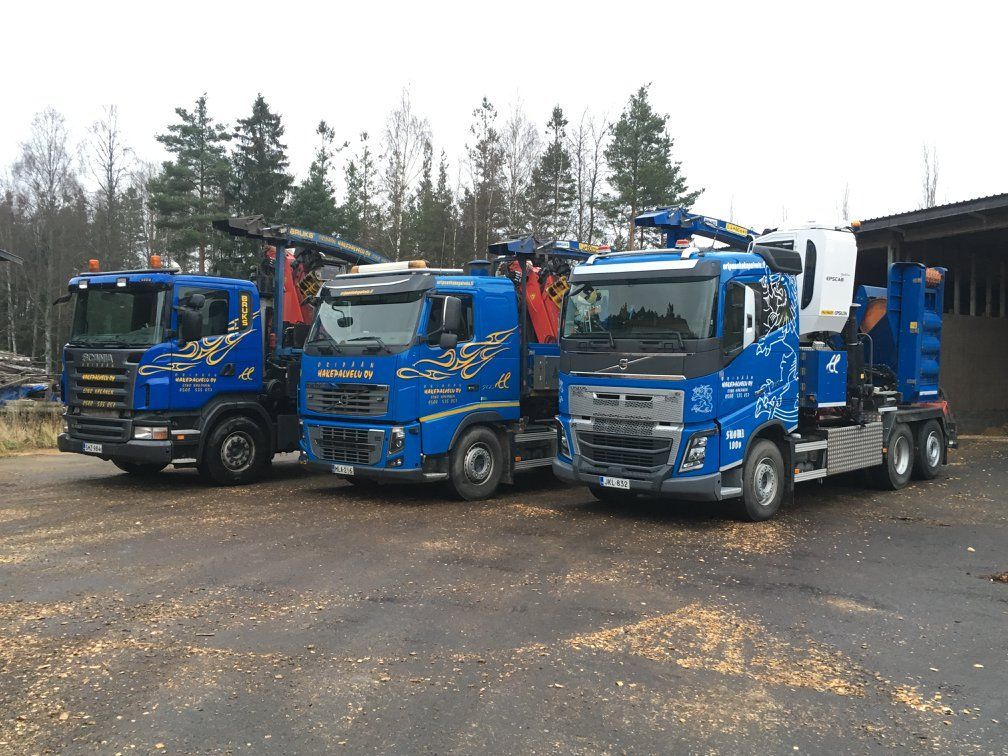 Kolme sinistä kuorma-autoa on pysäköity vierekkäin