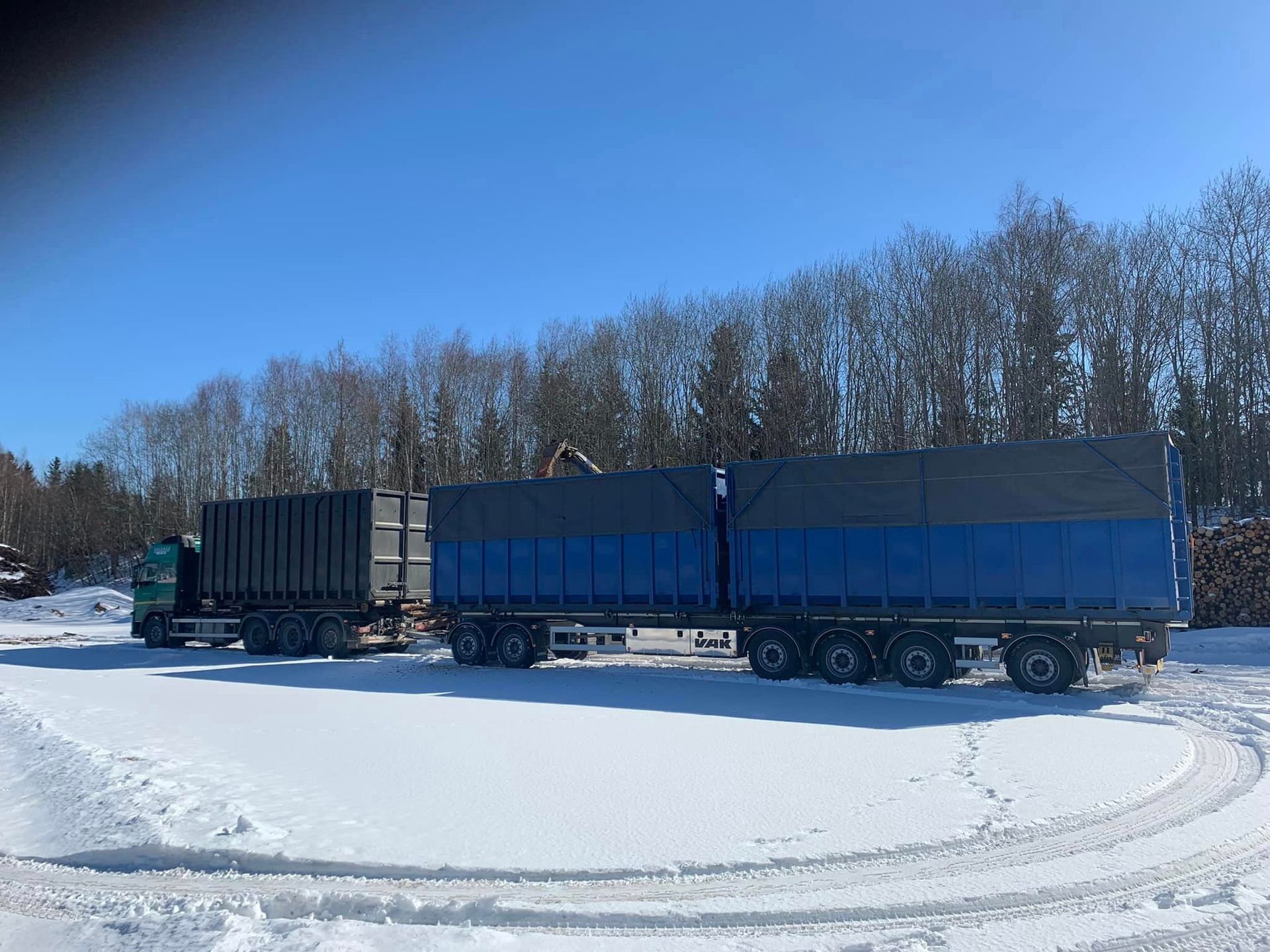 Perävaunuja pysäköitynä lumisella pellolla.