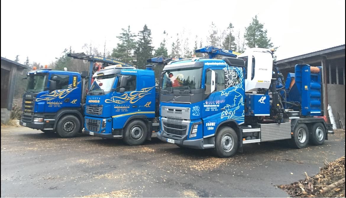 Kolme sinistä kuorma-autoa on pysäköity vierekkäin.