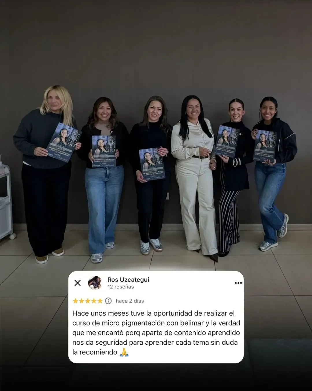 Seis personas están de pie en el interior, apoyadas contra una pared lisa, sosteniendo objetos iguales y posando para una foto de grupo.