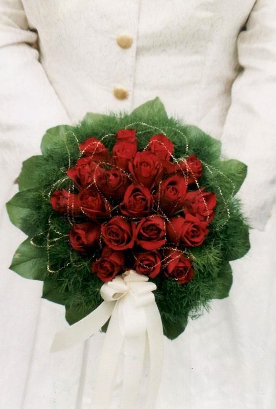 Eine Frau im weißen Kittel hält einen Strauß roter Rosen