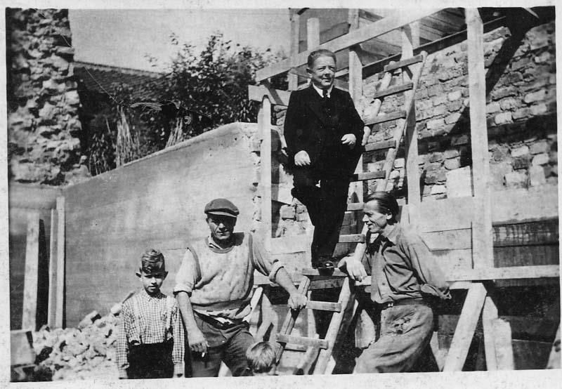 Auf einem Schwarzweißfoto steht eine Gruppe Männer auf einer Treppe.