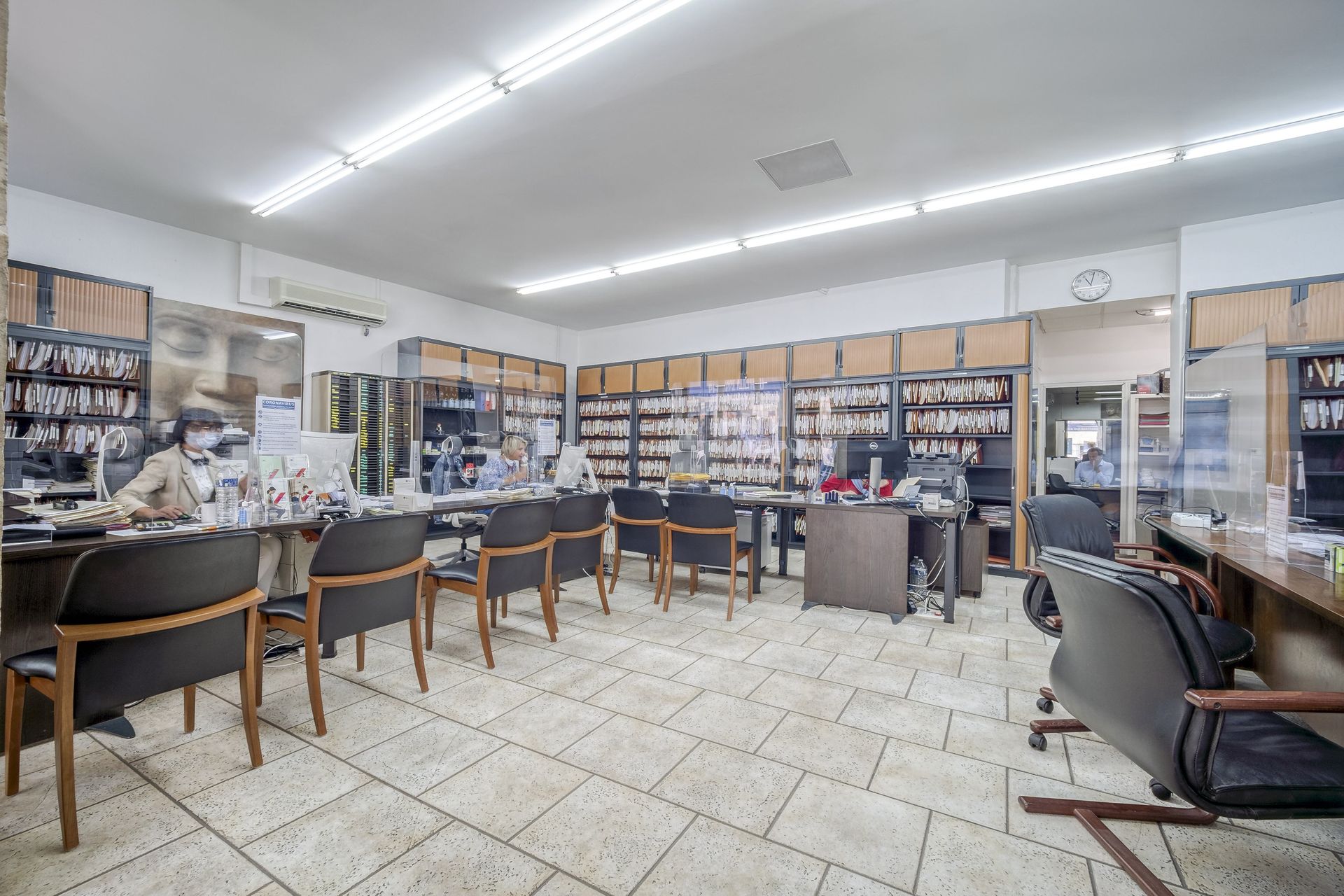 Intérieur de l'agence avec étagères de documents, bureaux et sièges