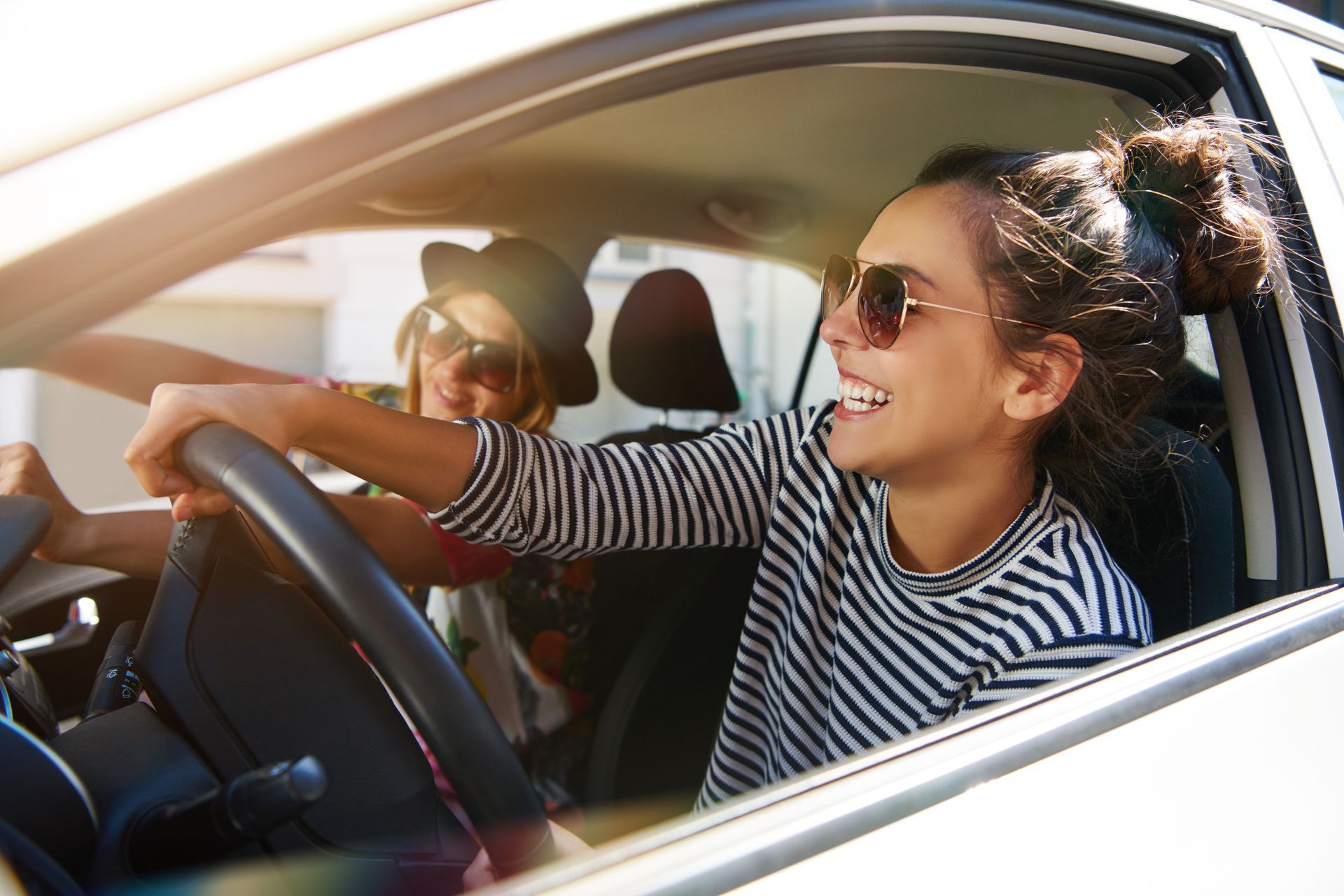 Jeune femme souriante au volant d'une voiture avec une passagère