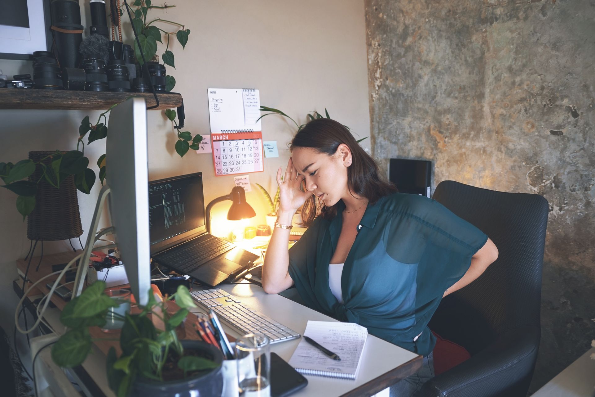 Jeune femme pensive accoudée à son bureau